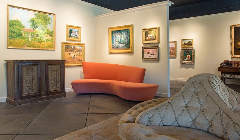 A photograph of the Interior of Stanford Fine Art, featuring most notably an orange mid century modern couch by Vladimir Kagan.