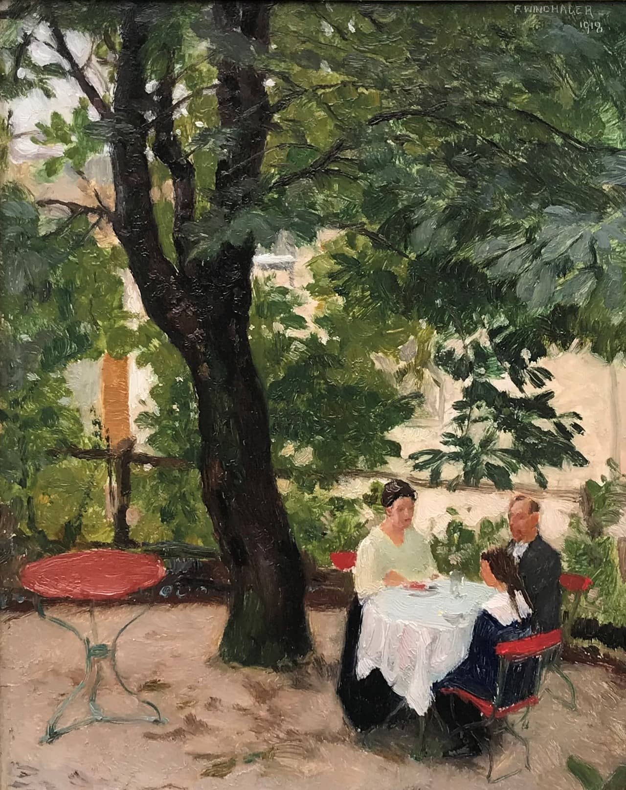 Windhager's Dining on a terrace. Set in an outdoor cafe in Austria, a well-dressed couple and their daughter prepare for lunch. Large tree in the background.